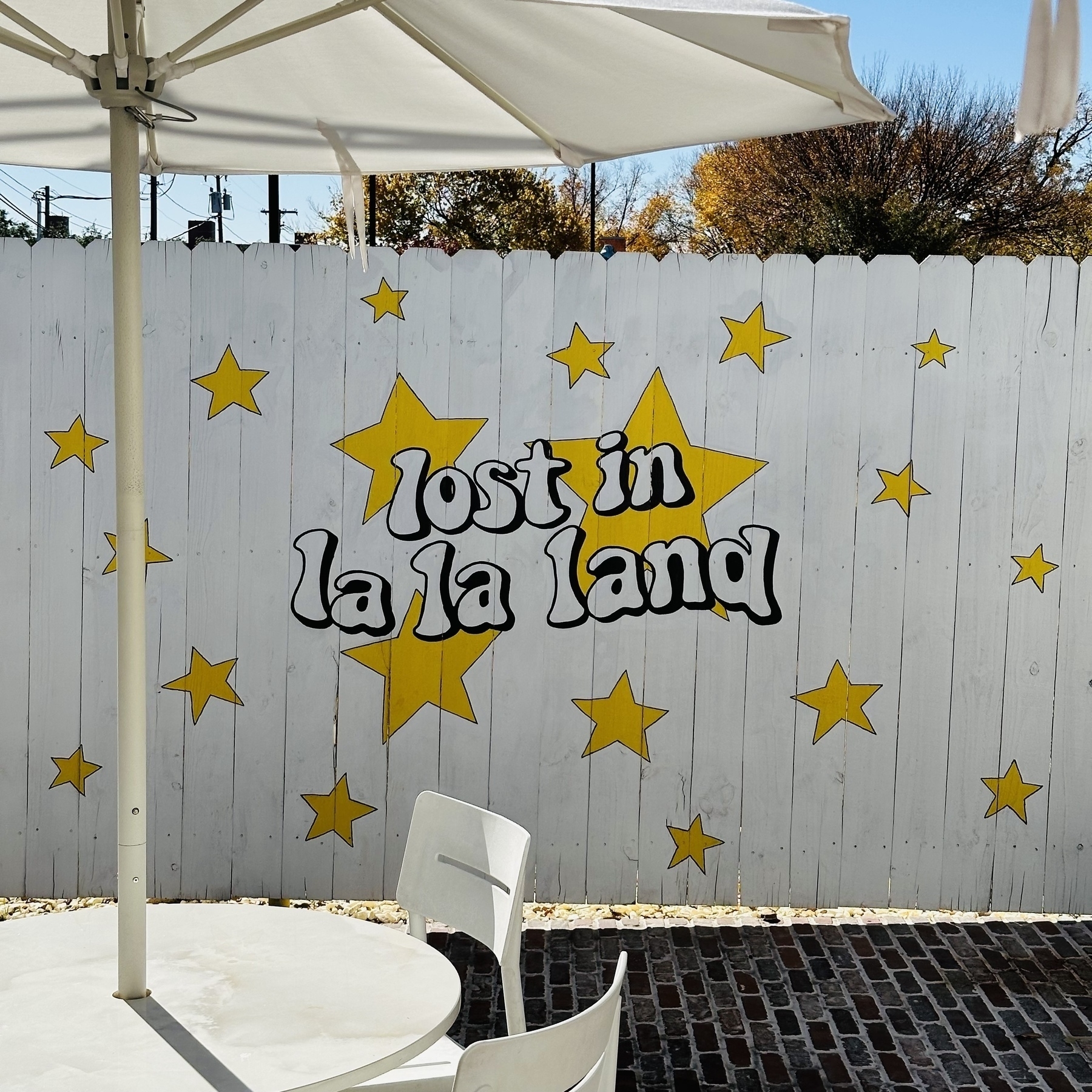 Outside patio, fence with “lost in la la land” painted on it with yellow stars.