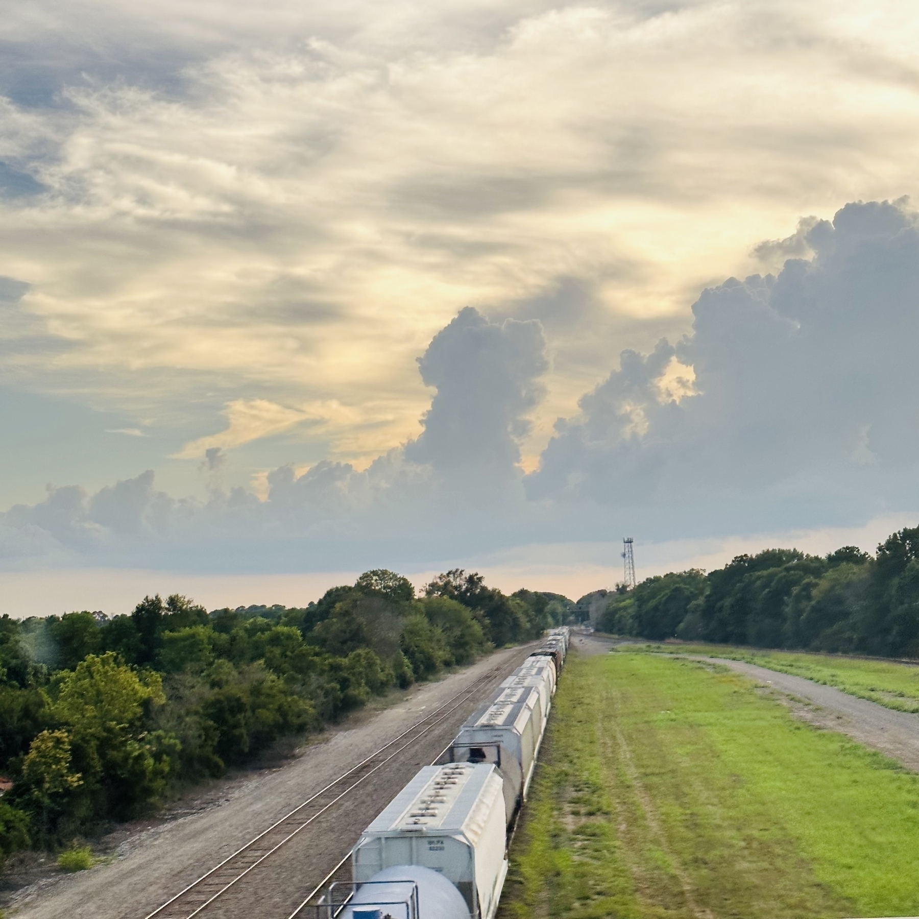 View from an overpass in Lafayette. Freight train on tracks and clouds before sunset.