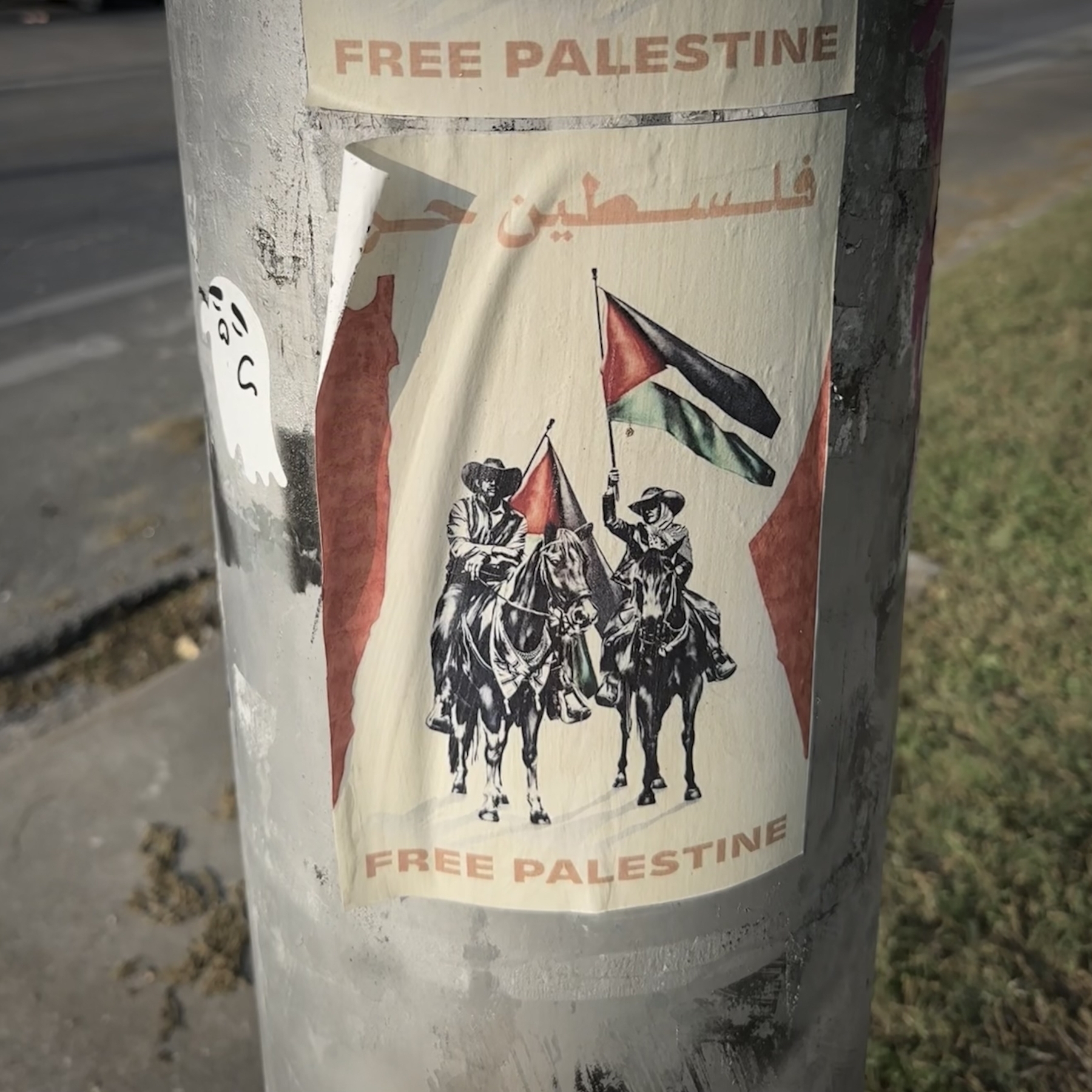 A weathered poster on a pole depicts figures on horseback, the Palestinian flag, and the text Free Palestine.