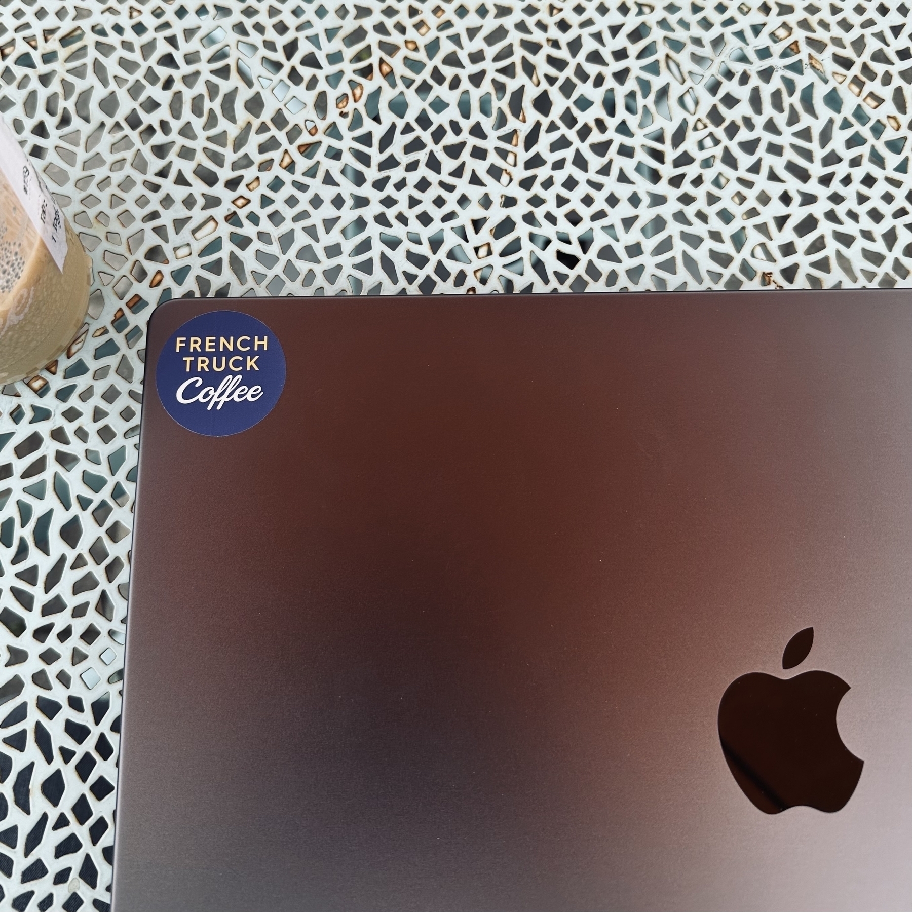 French Truck Coffee sticker on MacBook Pro with iced latter in the corner on outside blue table.