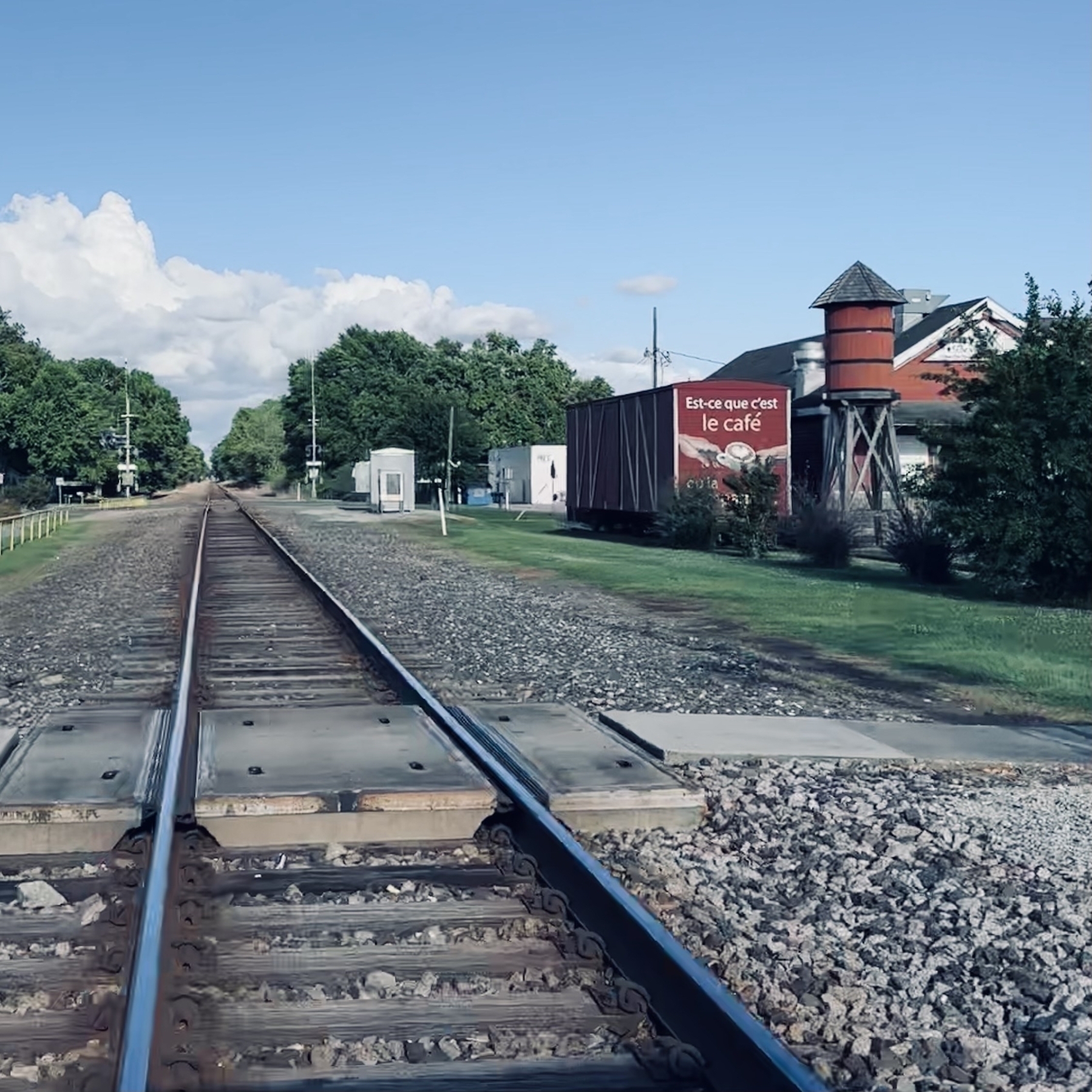 Train tracks with old boxcar and building in background.