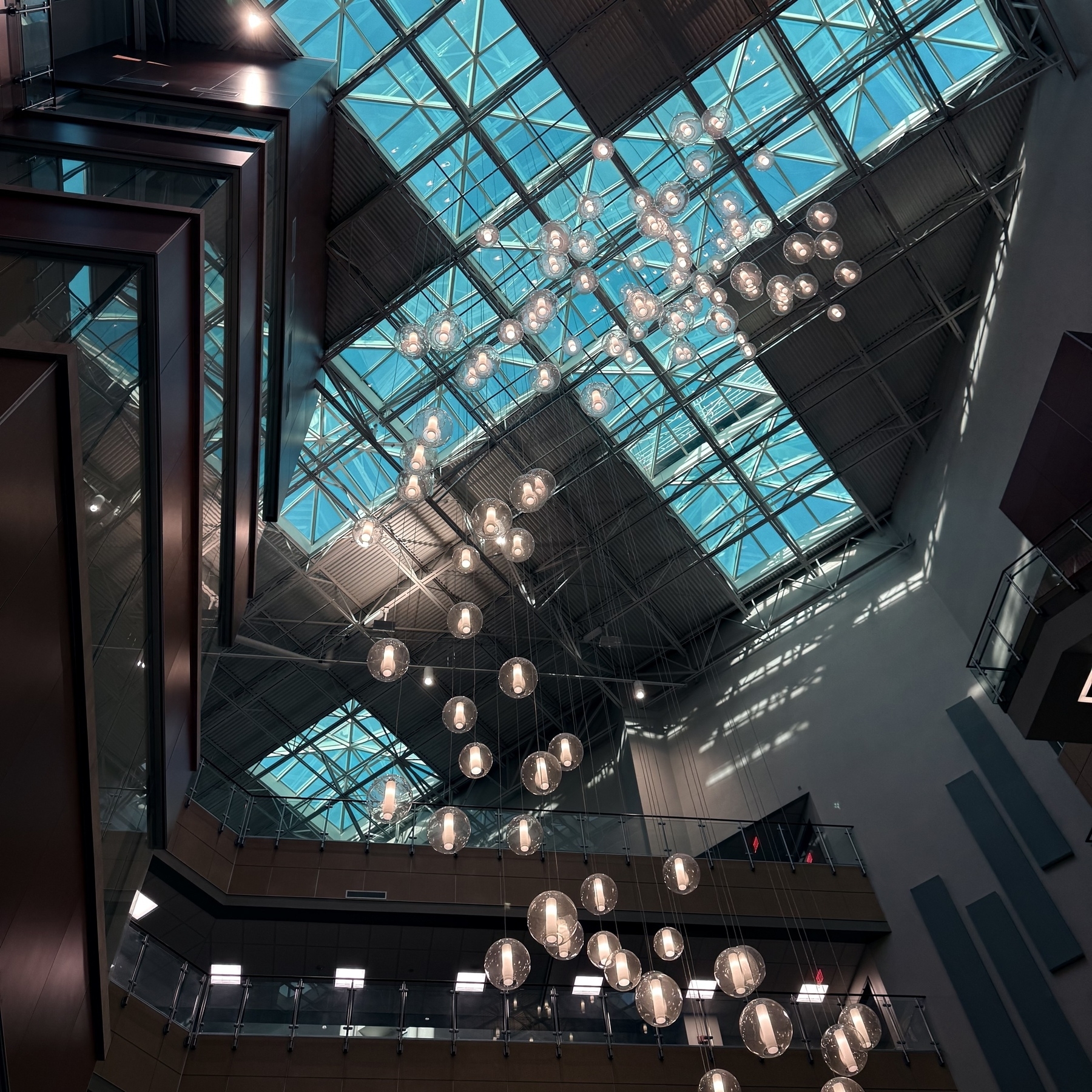 Hospital glass ceiling with hanging spherical light fixtures.