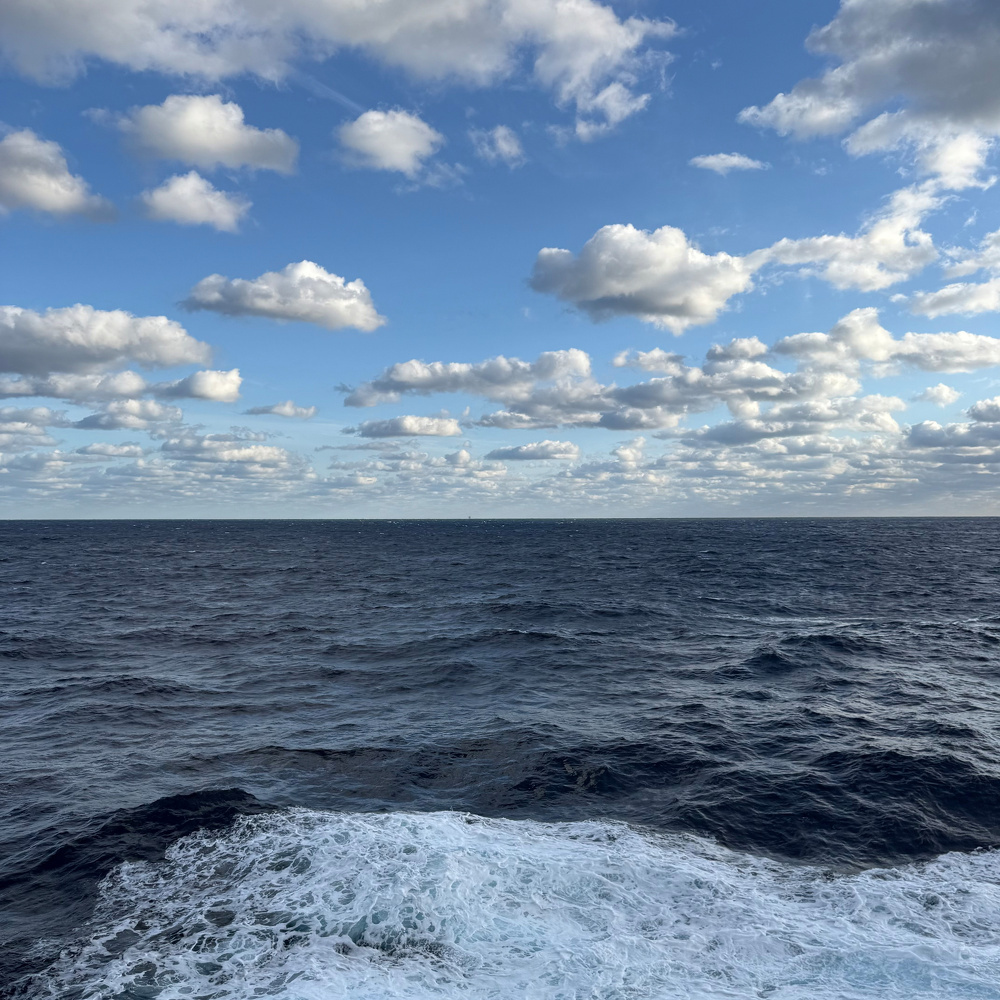 Ocean waves stretch out under a partly cloudy sky.