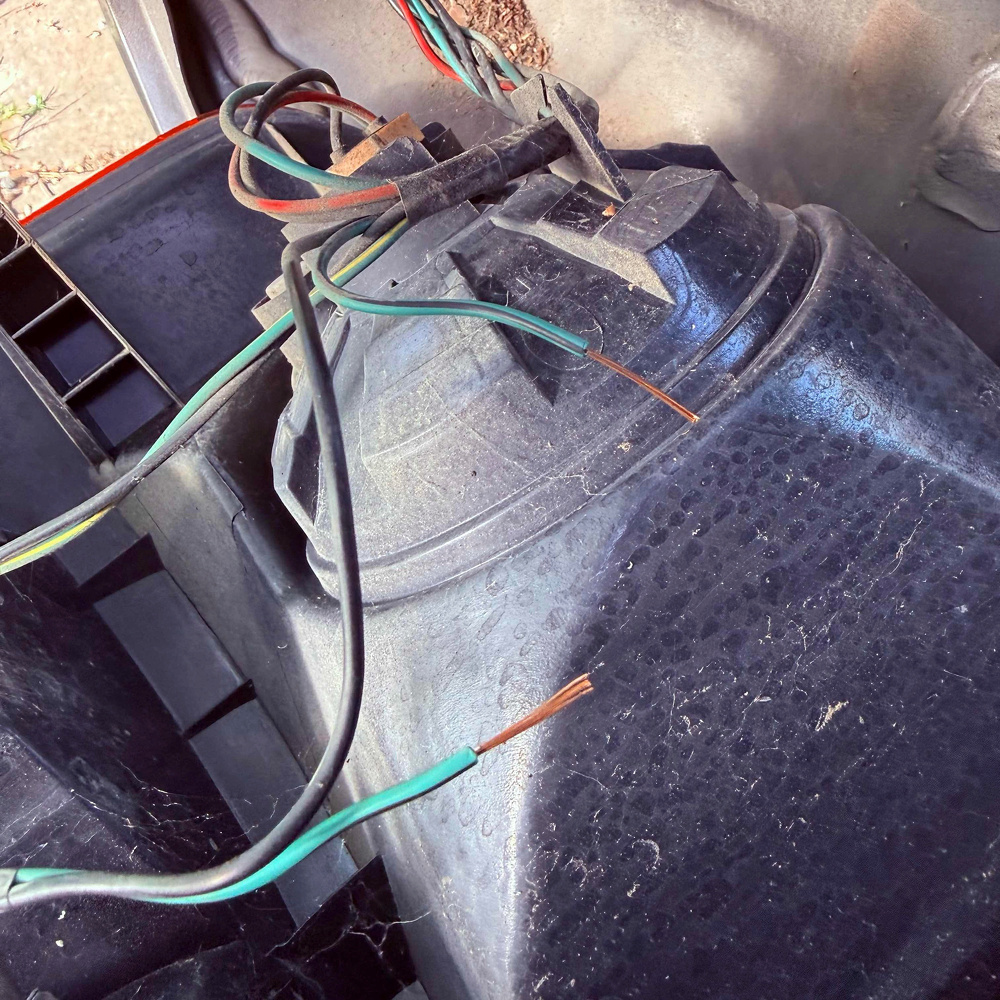 Several exposed electrical wires are connected to a black plastic component, possibly part of a vehicle's electrical system or lighting assembly.