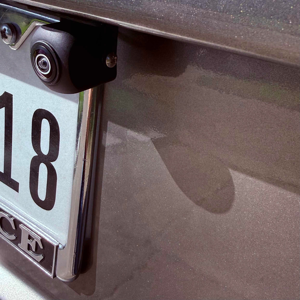 A close-up view of a car's rear license plate with a mounted backup camera above the plate.