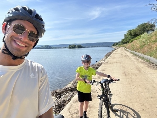 Nearly at the end of their bike adventure, father and son posing for one last photo, this one by the Susquahanna River in Harrisburg Pennsylvania
