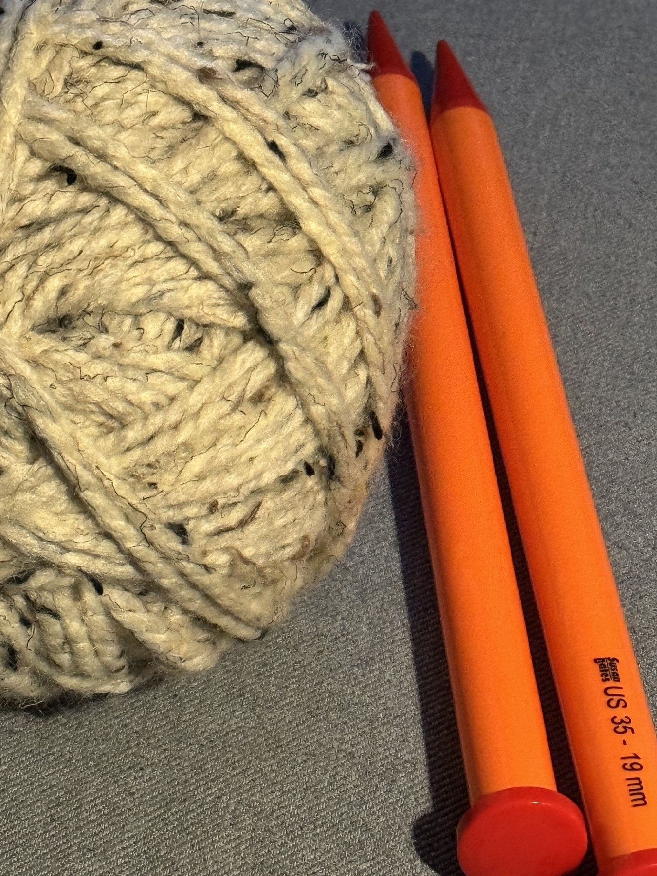 Ball of yarn next to two knitting needles. 