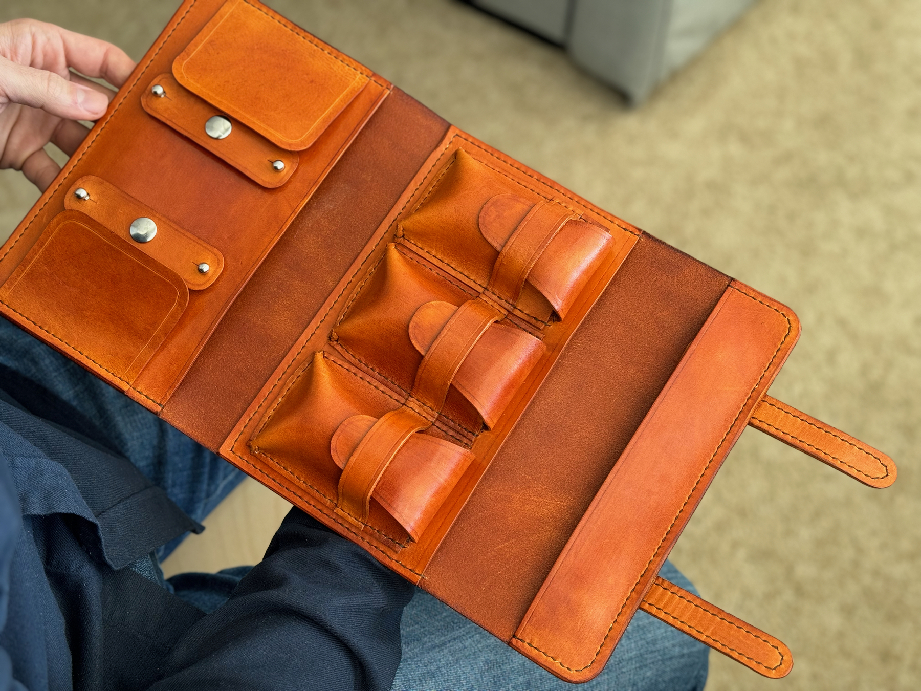 custom leather cigar case shown open with two primary sections. one on the very left for holding cigar tubes and similar sized items, and then a section in the center with three pockets (one each for lighter, cutter, etc).