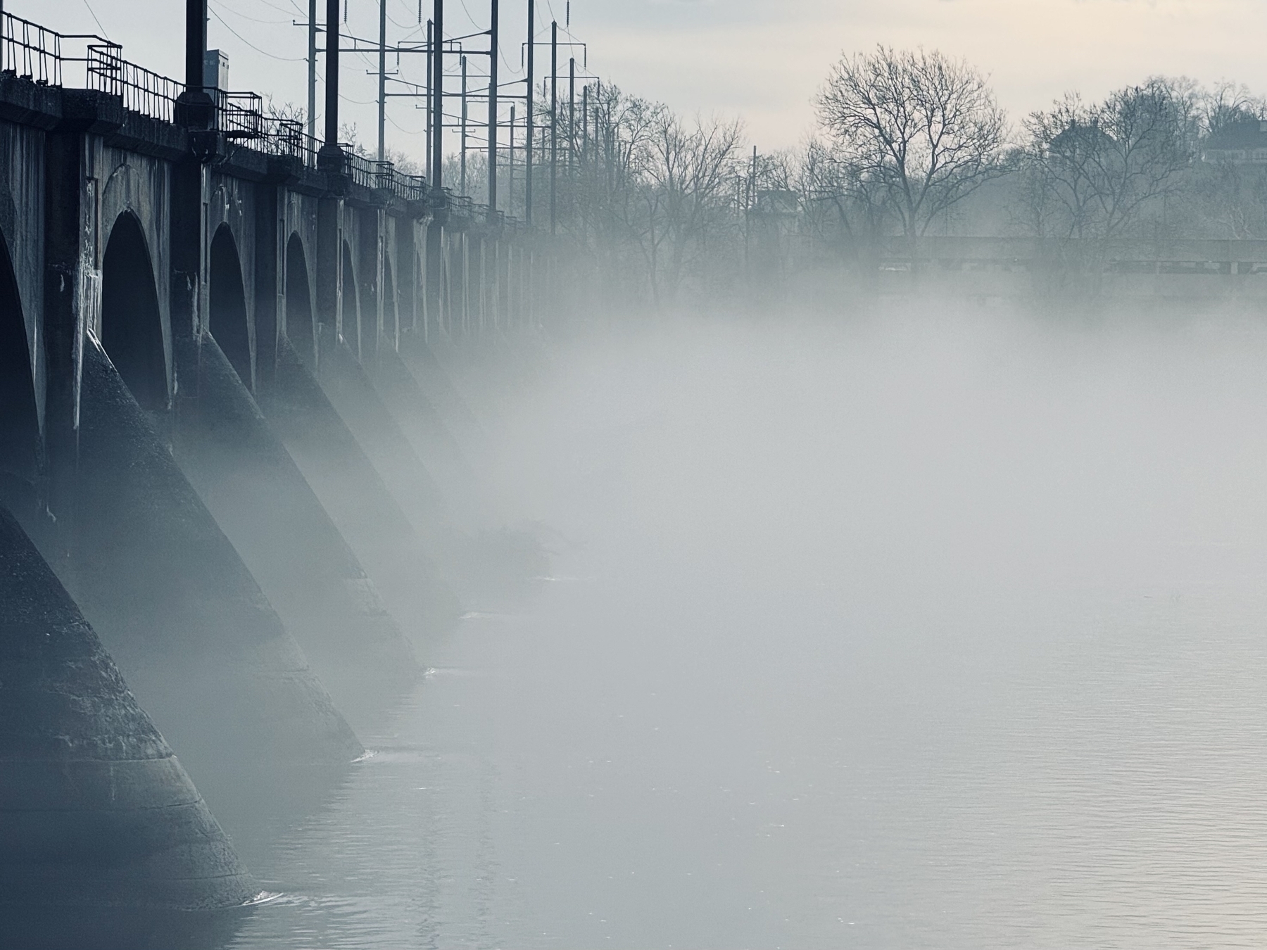 Fog over the Susquehanna river ins Harrisburg Pennsylvania an unused train bridge hovering above. 