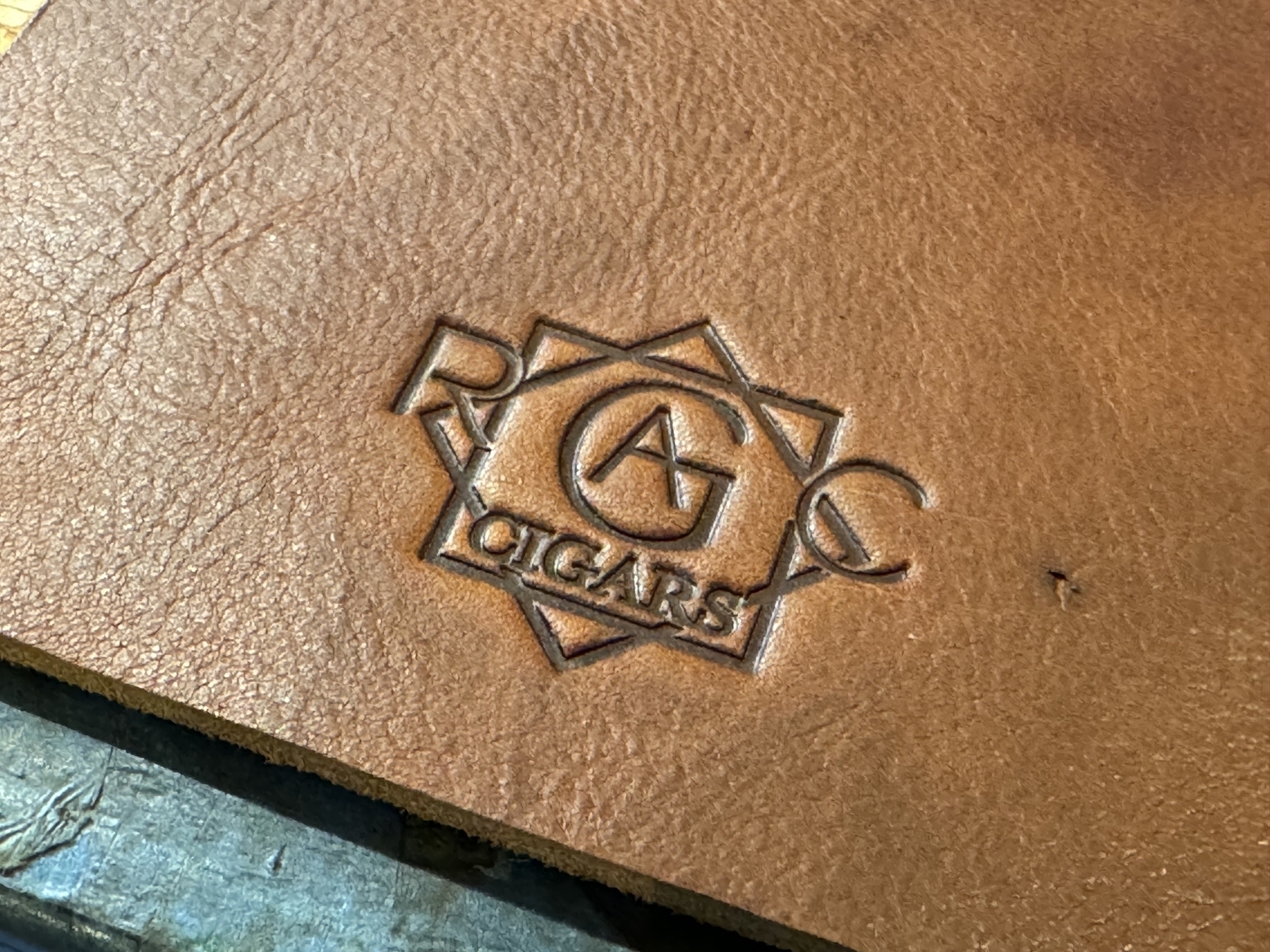 A piece of leather features an embossed logo with a geometric design and the text "CIGARS".