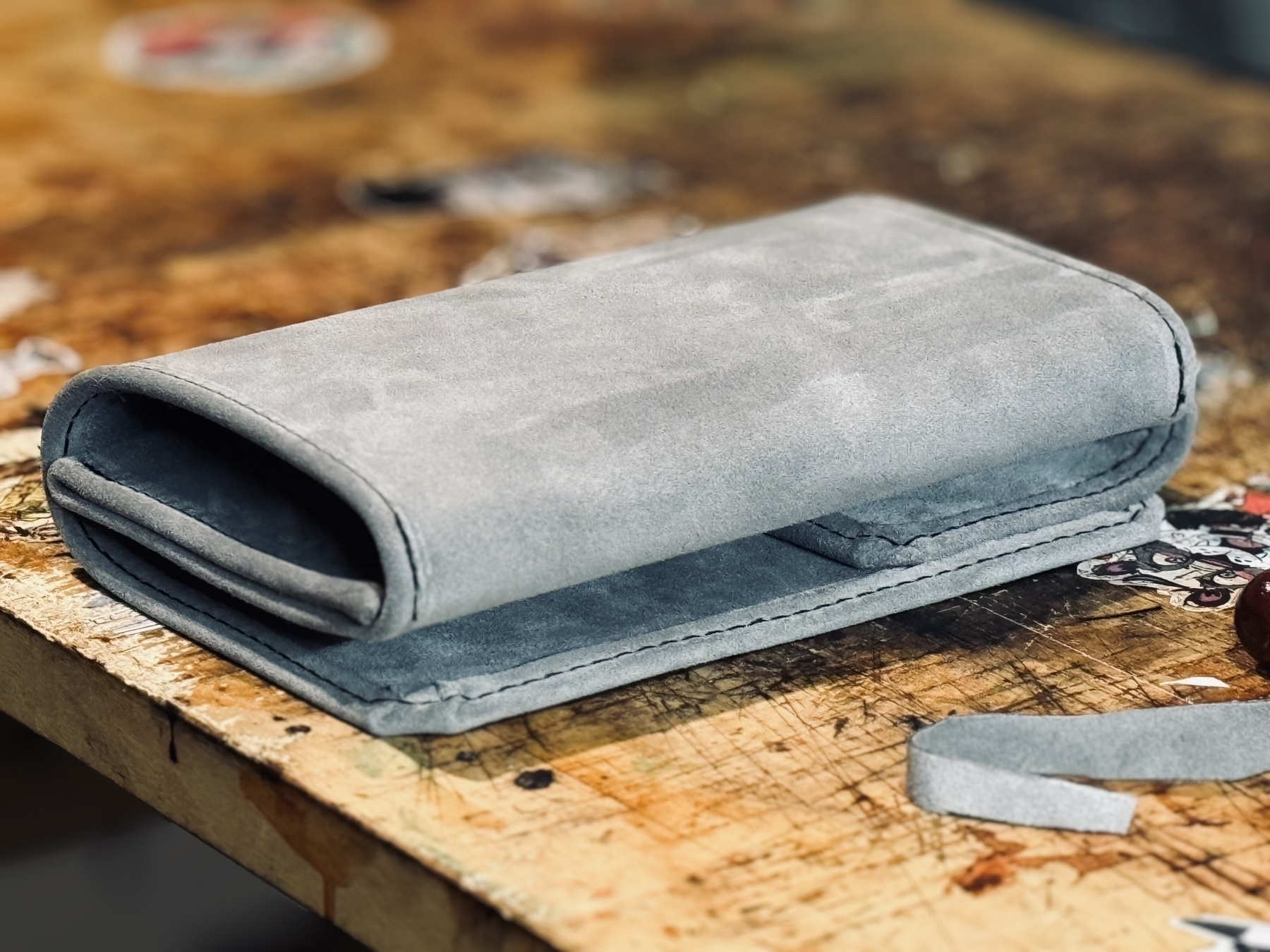 A folded gray suede case is placed on a wooden surface.