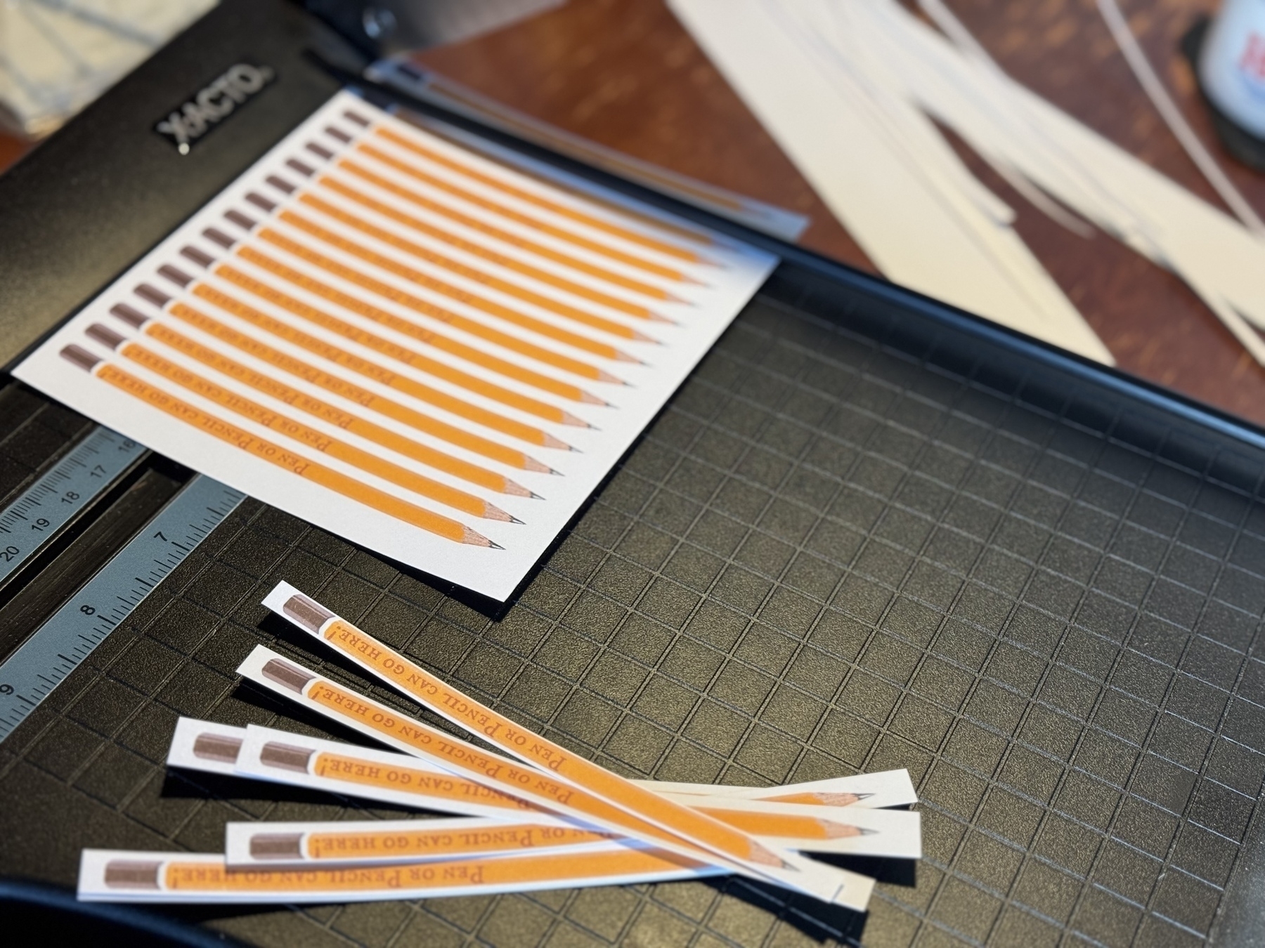 A paper trimmer is shown alongside multiple strips of paper with printed designs.