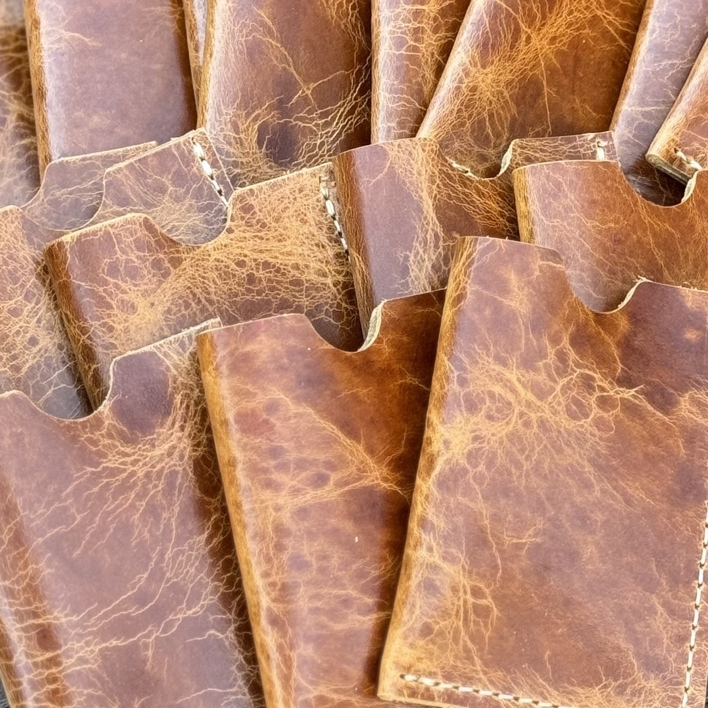 Several brown leather card holders with visible stitching are arranged closely together.