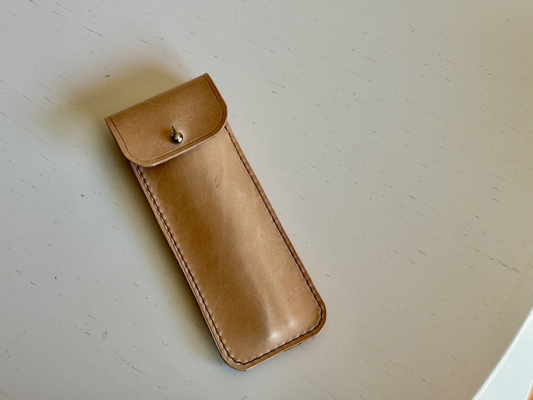 Natural tan leather fountain pen case with a nickel plate button stud closure. 