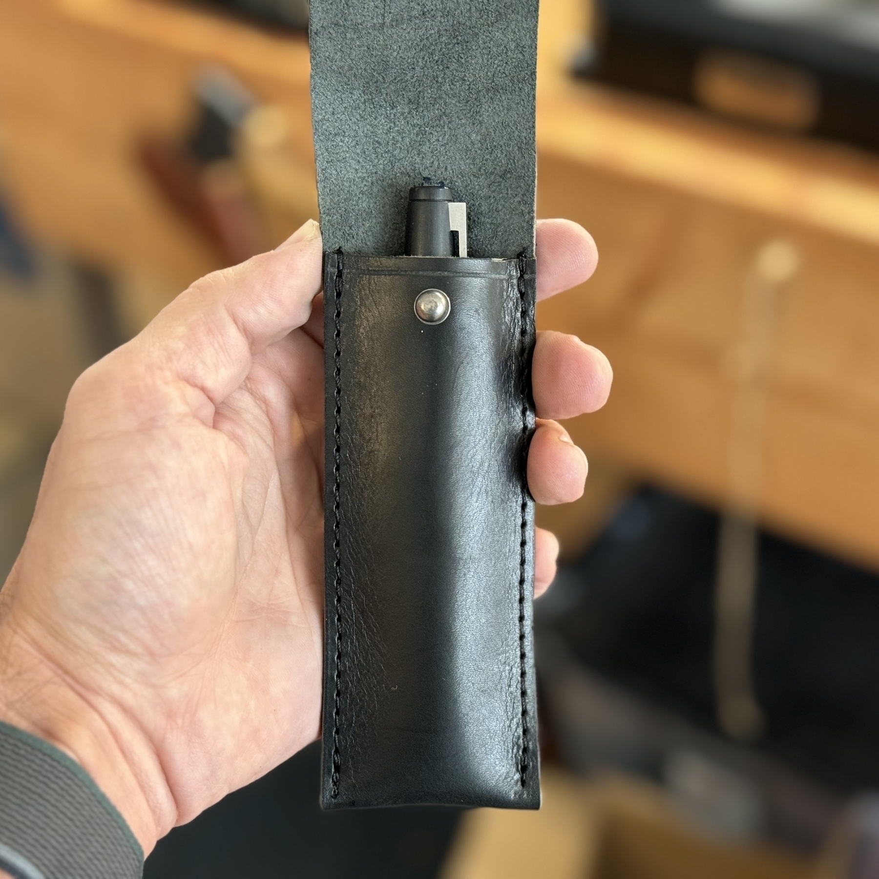 Black leather fountain pen case shown open containing a single pen. 