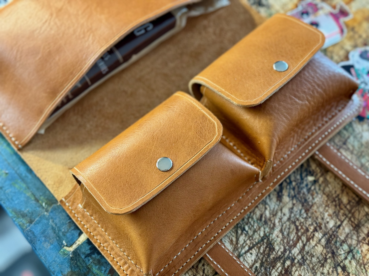 Two accessory pockets shown closed on leather cigar case. Closure utilizes magnetic snaps.