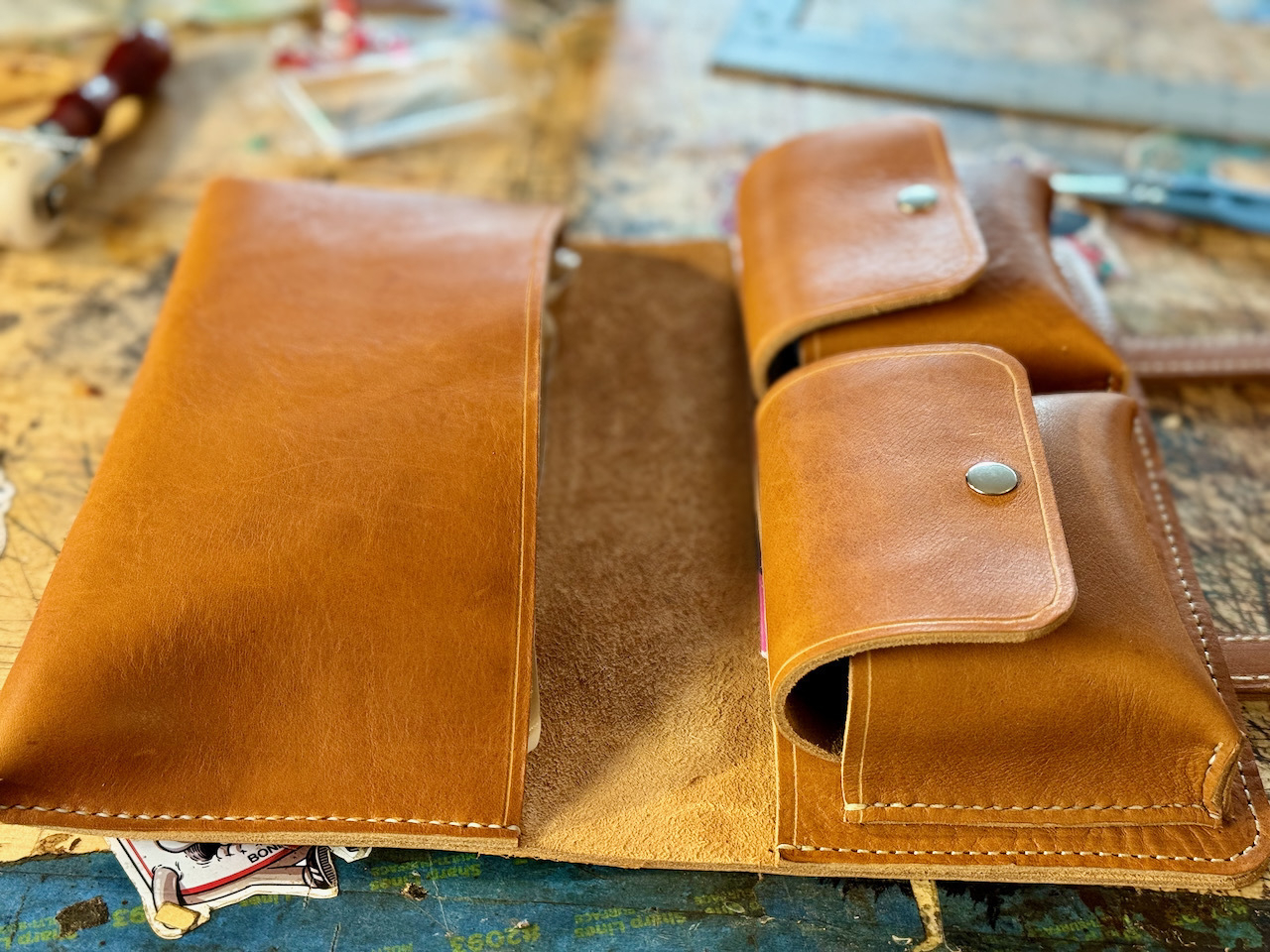 Viewing a leather cigar case from the bottom, seeing the main cigar pocket on the left which is sized to hold a small boveda humidor bag and on the right the two cigar tool pockets are shown closed, each one is sized to fit larger cigar cutters and cigar butane lighters.