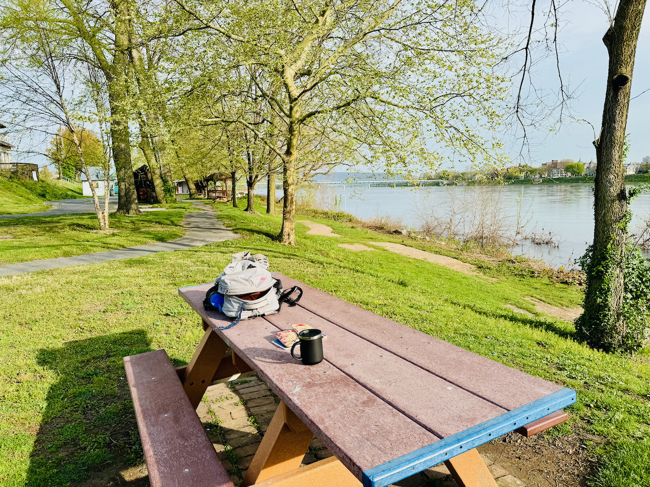 park bench at City Island in Harrisburg Pennsylvania. Backpack on the table, notebooks and coffee too. Time to write!