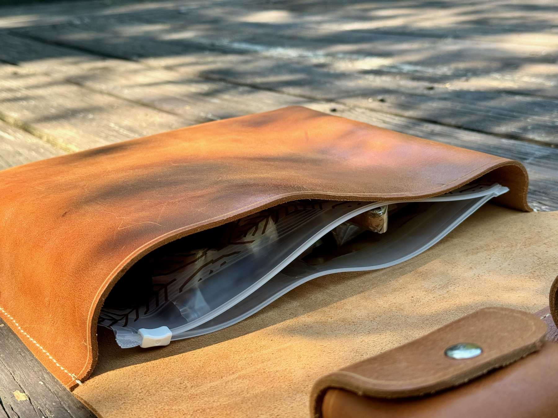 A brown leather cigar case with a snap closure is partially open, revealing a medium Boveda humidor bag inside.