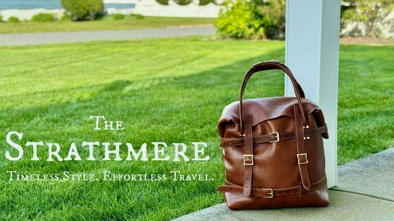 The strathmere promo image - Leather weekend bag resting against a porch column at a beach house