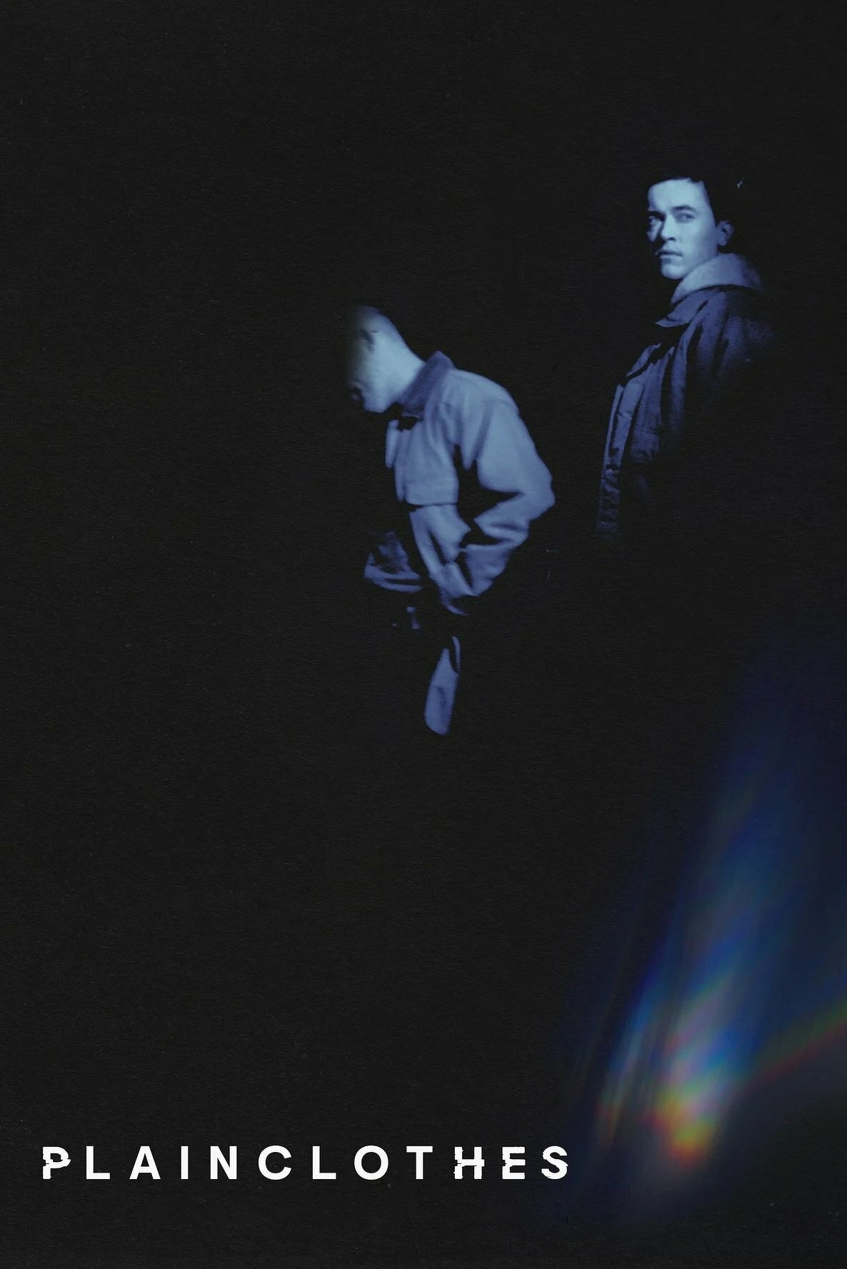 Two individuals stand in a dark, shadowy environment with low lighting. One person is facing downward, partially hidden, while the other looks forward. Both are wearing jackets. The image includes a colorful lens flare effect on the right side and the word "PLAINCLOTHES" in bold, white, fragmented text at the bottom.