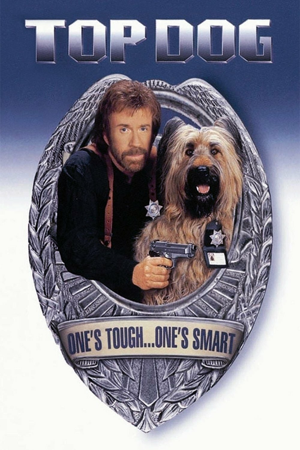 A movie poster features a large metallic police badge with an oval frame. Inside the frame, a bearded man with light brown hair wearing a black shirt and brown shoulder holsters holds a pistol in his right hand. Beside him is a large, shaggy tan dog with a black snout and open mouth, wearing a small police badge and an ID tag on its collar. Above the badge, bold metallic letters read “TOP DOG.” At the bottom of the badge, a silver ribbon bears the phrase “ONE’S TOUGH…ONE’S SMART.” The background is a gradient of dark blue to white.