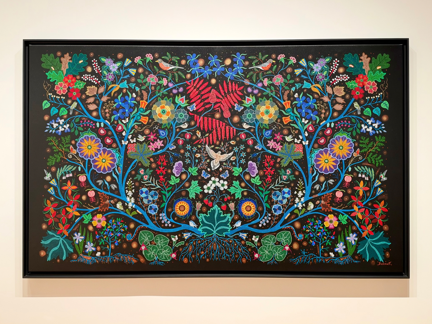 A vibrant, symmetrical painting depicts colorful flowers, birds, butterflies, and leafy branches against a dark background.