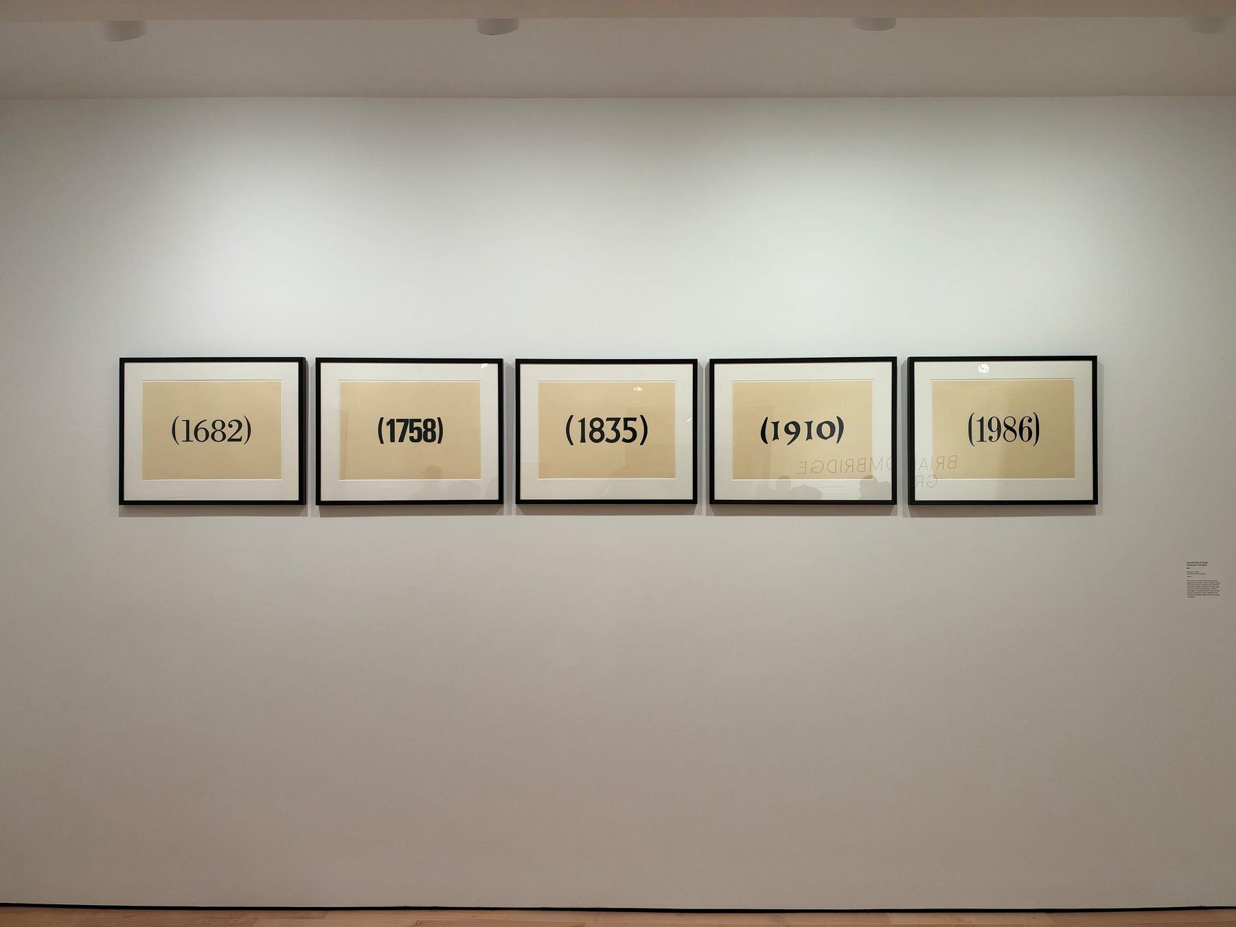 Five framed artworks displaying years in parentheses—1682, 1758, 1835, 1910, and 1986—are hung in a horizontal row on a white gallery wall.