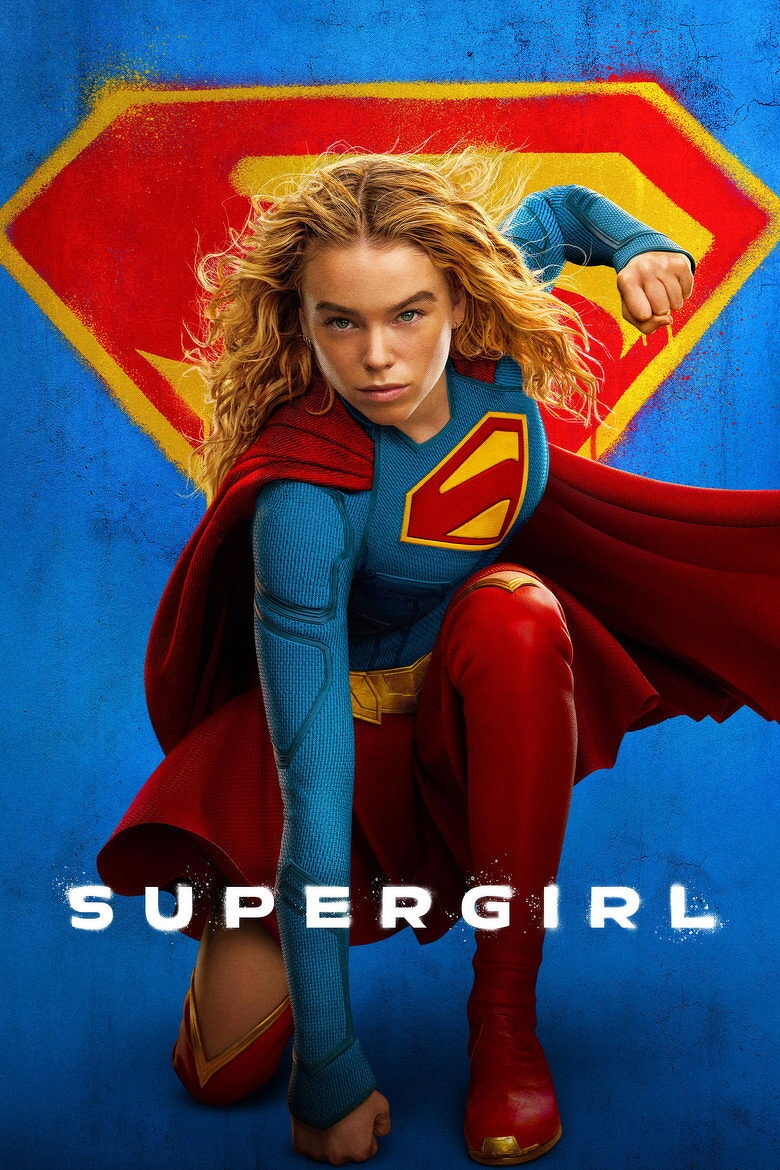 A young woman dressed as Supergirl is kneeling on one knee in a dynamic pose with one fist on the ground and the other arm bent and raised behind her. She has long, wavy blonde hair flowing behind her and a determined expression on her face. She is wearing a blue textured suit with a red and yellow “S” emblem on her chest, a red cape, red boots, and red pants. Behind her is a large, stylized yellow and red Superman emblem on a textured blue background. The word “SUPERGIRL” appears in bold white letters at the bottom of the image.