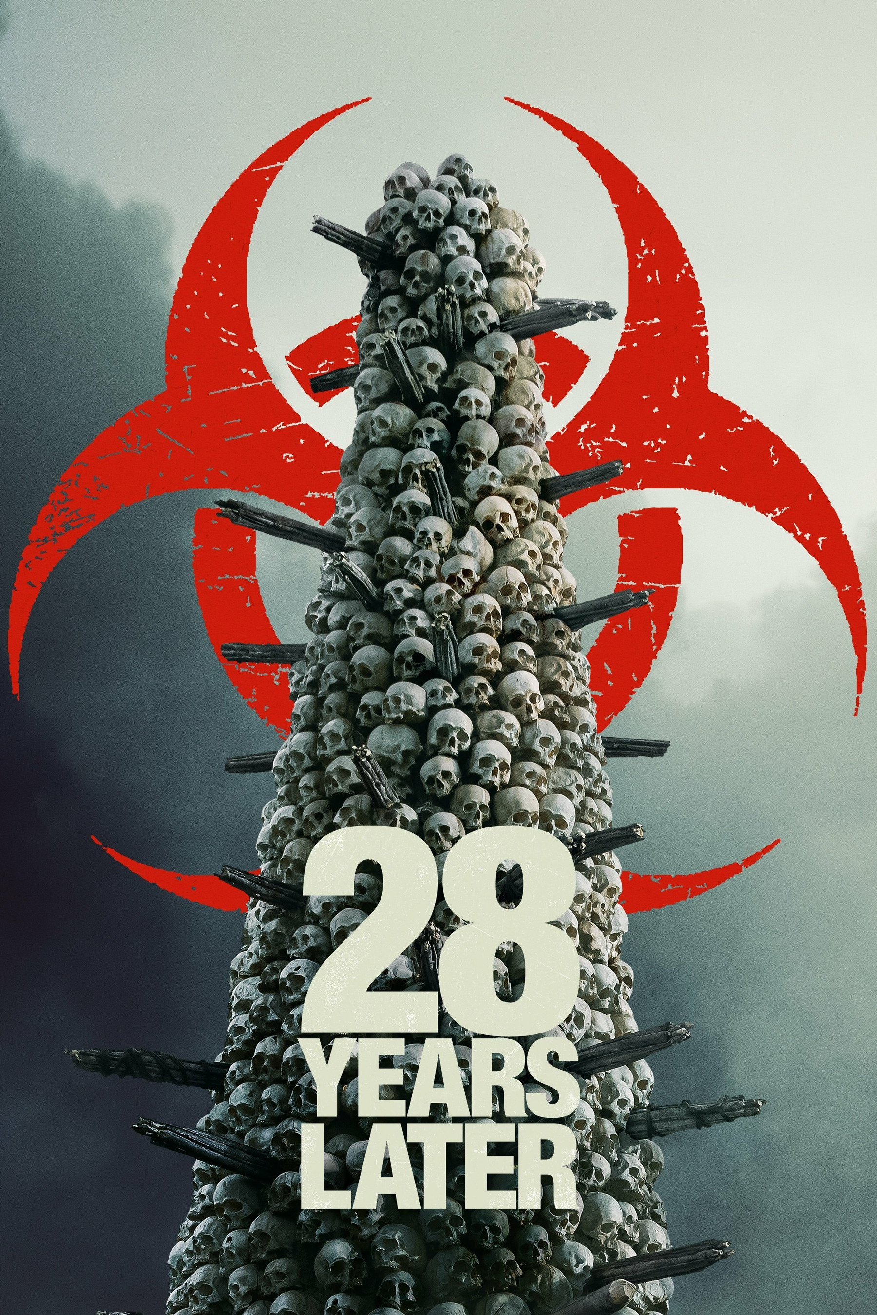 The image features a towering stack of skulls with protruding sticks, creating an ominous and unsettling visual. Behind the skulls is a large, red biohazard symbol, adding to the dystopian theme. The foreground displays the text "28 Years Later" in bold white letters. The background is a cloudy sky, enhancing the dark and foreboding atmosphere.&10;