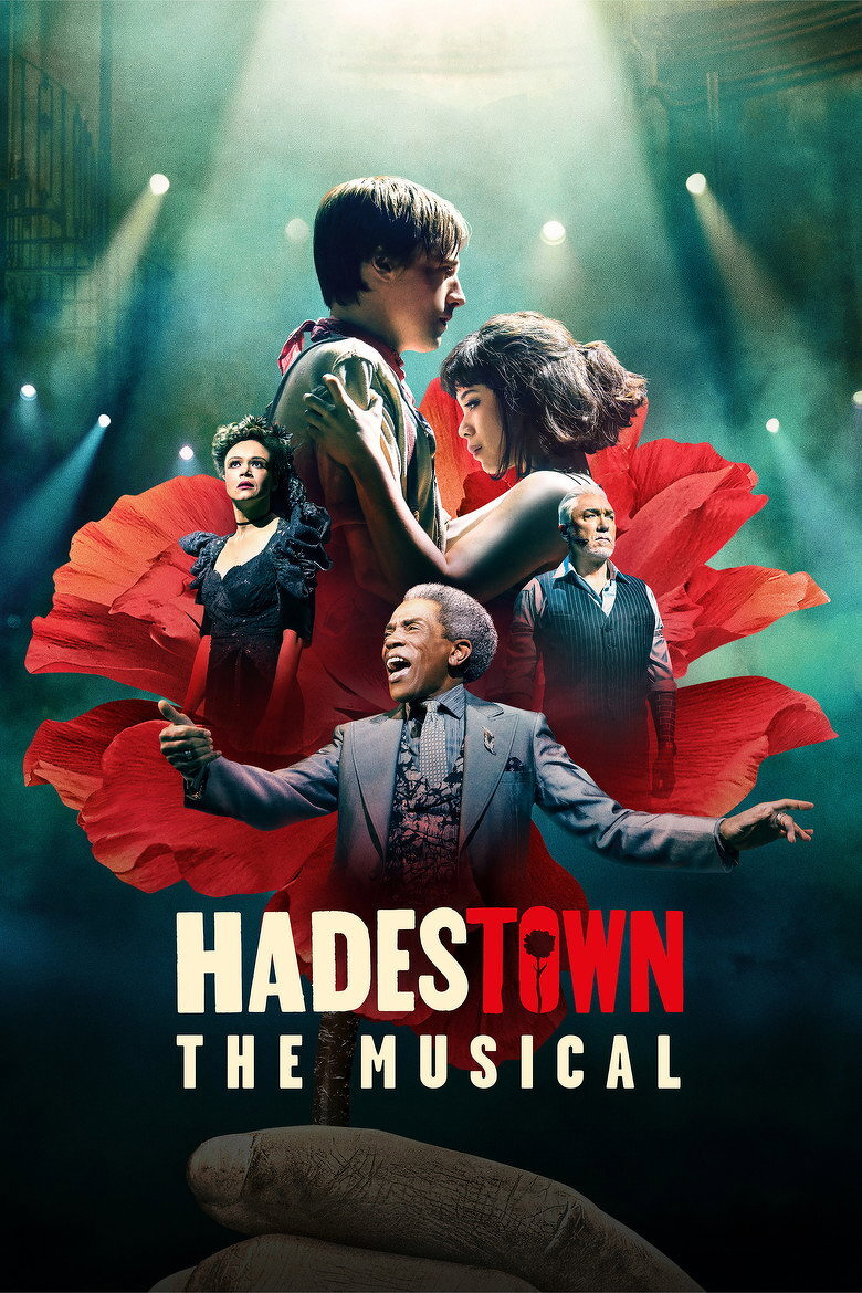 A promotional poster for the musical “Hadestown.” At the top, a young man and woman embrace, gazing at each other intensely, surrounded by a large red flower. Behind them are two other figures: a woman in a dark, elegant dress with a serious expression and a man in a dark vest with a stern face. In the foreground, a man in a grey suit spreads his arms wide, smiling and animated. Dramatic stage lighting with beams of light and misty, greenish-blue tones fills the background. The title “HADESTOWN” appears at the bottom in bold white and red letters, with the “O” shaped like a flower, followed by the words “THE MUSICAL” in smaller white letters. Large stone steps emerge from the bottom, leading into the scene.