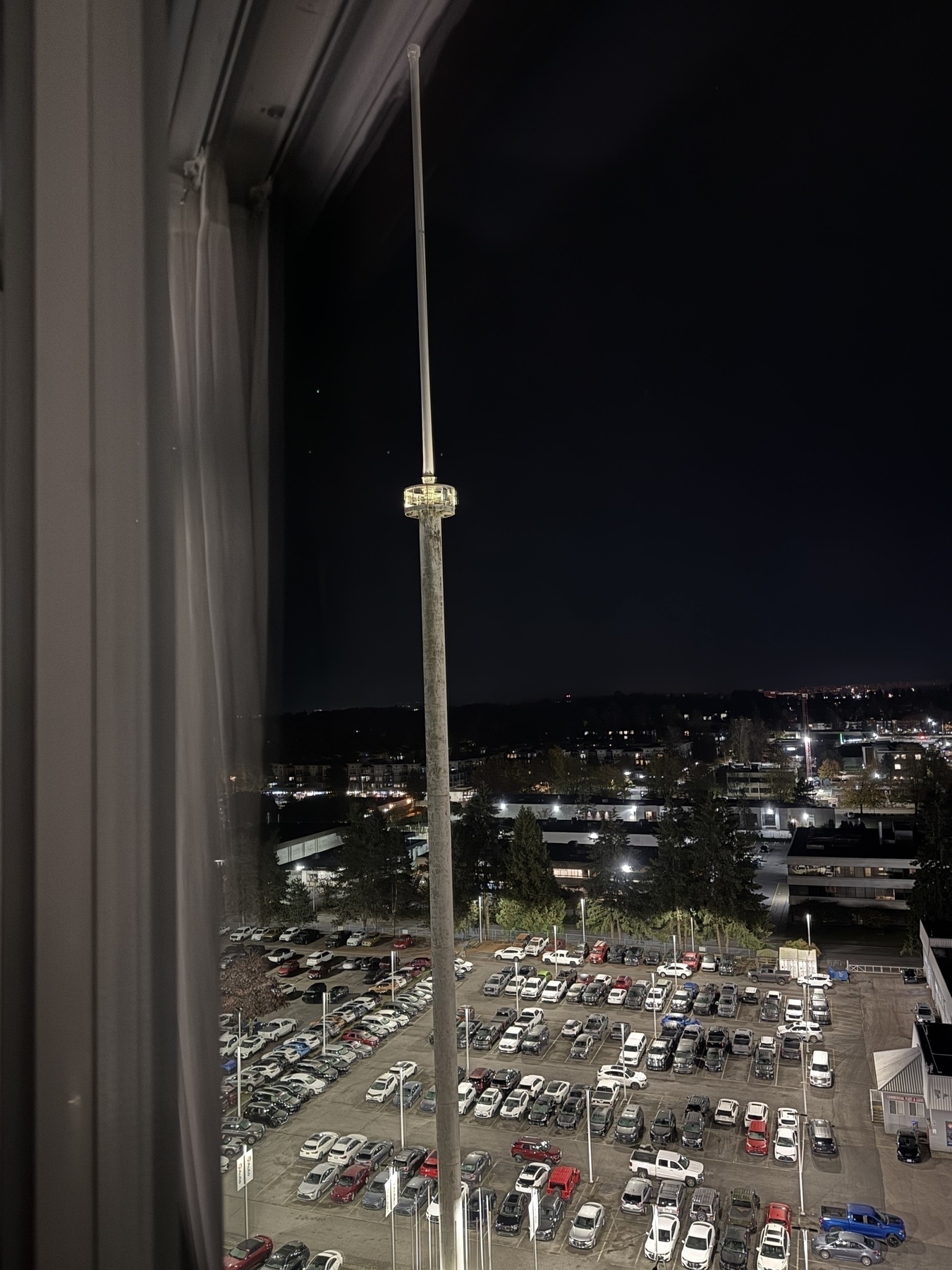 Photo of a long thin concrete tower, middle lit up against the night, and with people just barely visible inside&10;