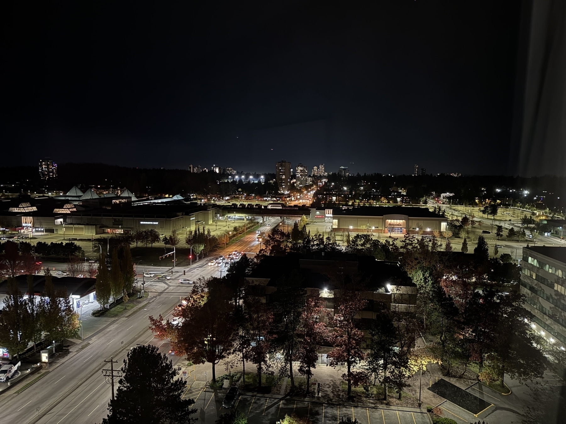 Photo of downtown Surrey seen from a distance at night, with high rises lit up against the dark.&10;