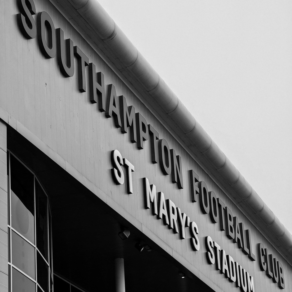 Southampton Football Club, St Mary’s Stadium signage crosses diagonally from top left to bottom right. Black and white.