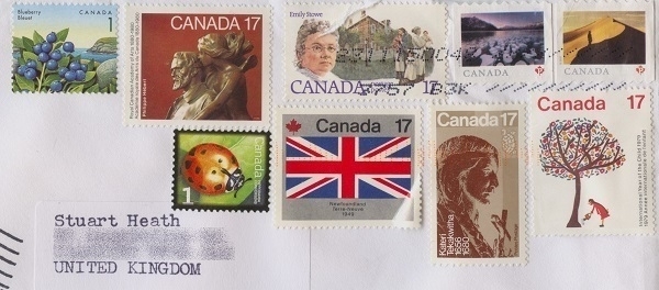 Part of an addressed envelope with nine assorted Canadian postage stamps on it.