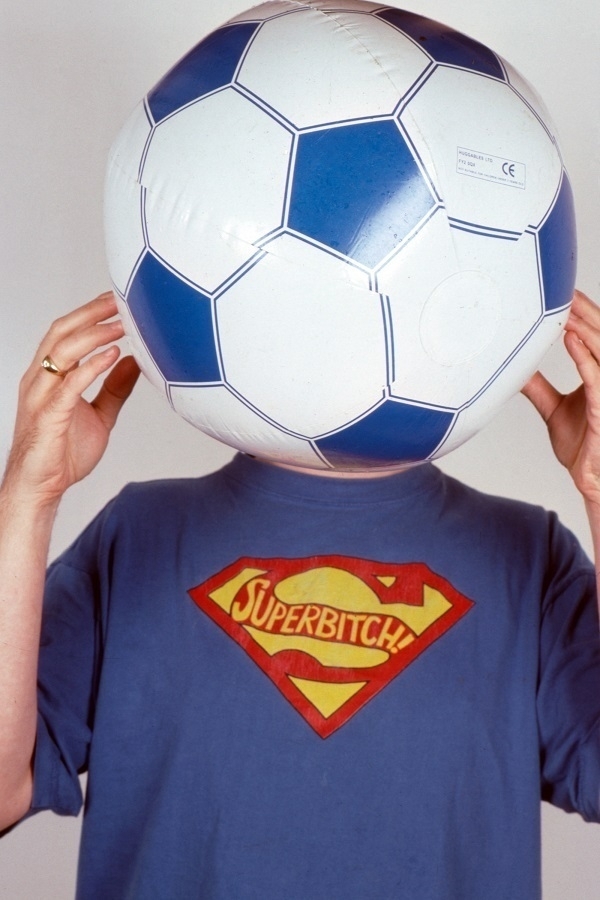 Self-portrait with face obscured by a child's football and wearing a 'Superbitch!' t-shirt