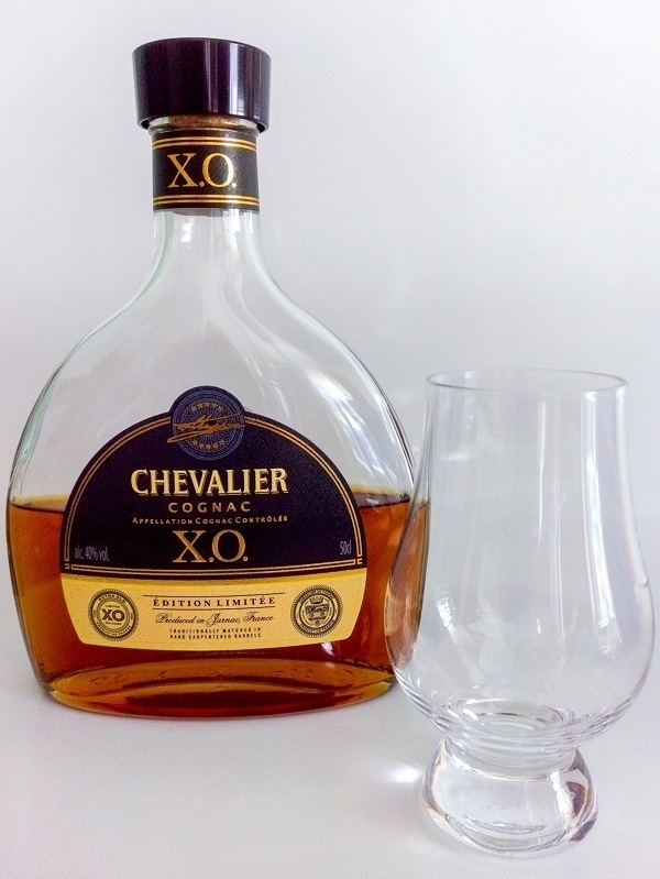 A less than full bottle of 'Chevalier' XO cognac and an empty glass.