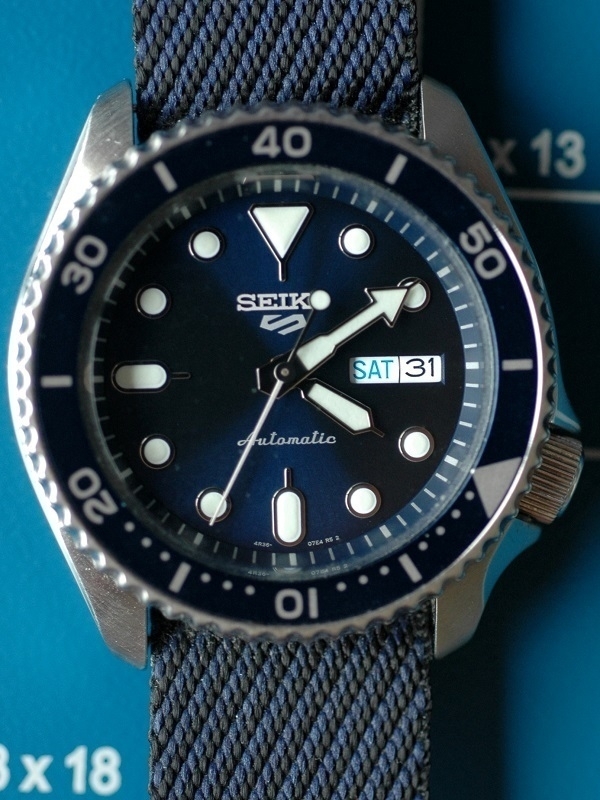 A Seiko 5 Sports wristwatch with a blue face and strap.