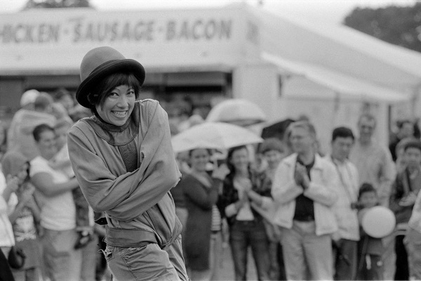 Black and white photo of a smiling escapologist mid performance.