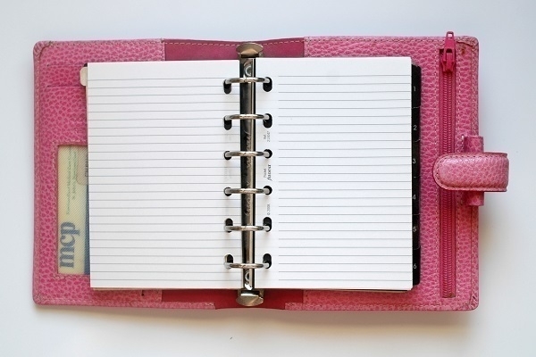 An open pocket-sized Filofax personal organiser bound in pink leather.