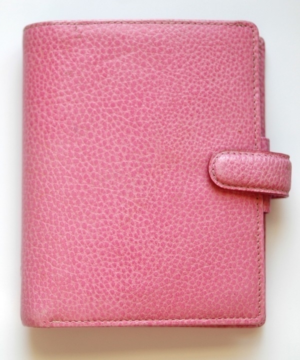A closed pocket-sized Filofax personal organiser bound in pink leather.