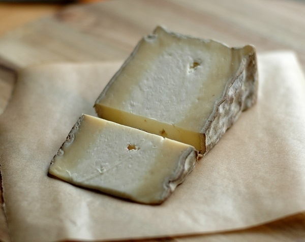 A wedge of Gorwydd caerphilly cheese with a smaller wedge cut off it.