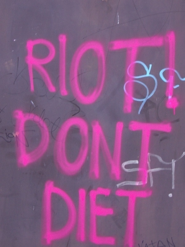Spray-painted graffiti text reading 'Riot! Don't Diet'
