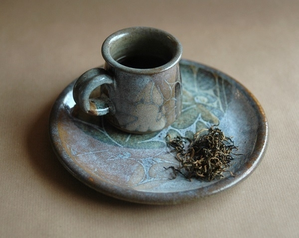 A cup of 'Jin Jun Mei' Chinese black tea with some of the tea leaves.