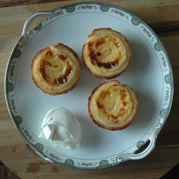 Three 'pastéis de nata' and a scoop of mascarpone on a plate.