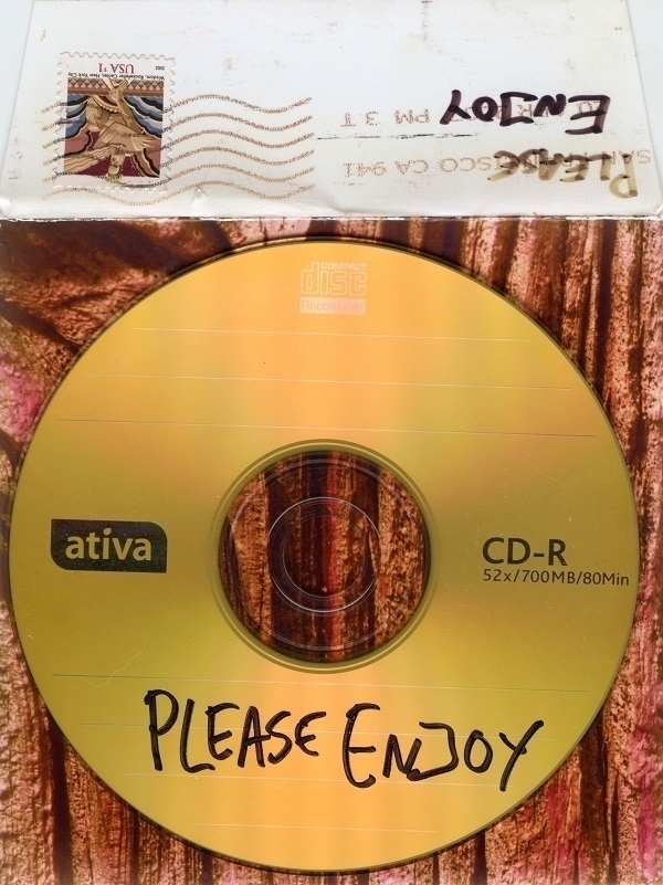 A CD-R with the words 'Please Enjoy' written on it, on top of the envelope in which it was sent to me.