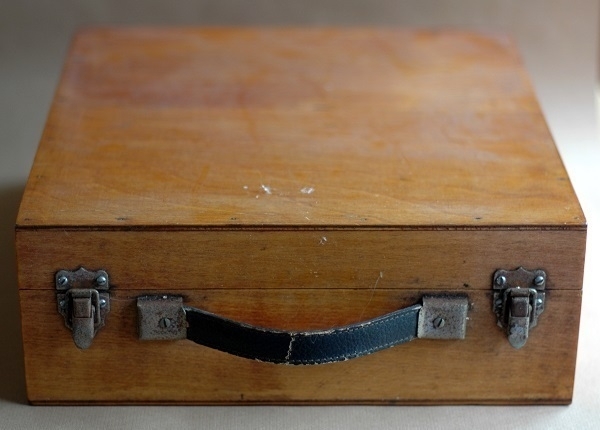 A wooden case with metal catches and a leather handle.