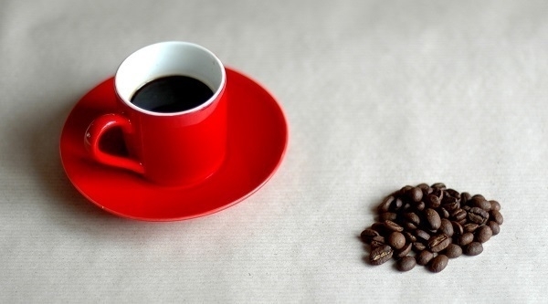 A red cup containing espresso made with the Bristol Coffee Company's 'Colombia Supremo' blend; along with some of the coffee beans.