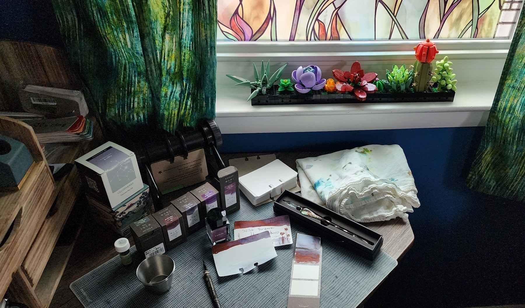 Photo of desk next to window with supplies laid out to create swatch cards for fountain pen ink