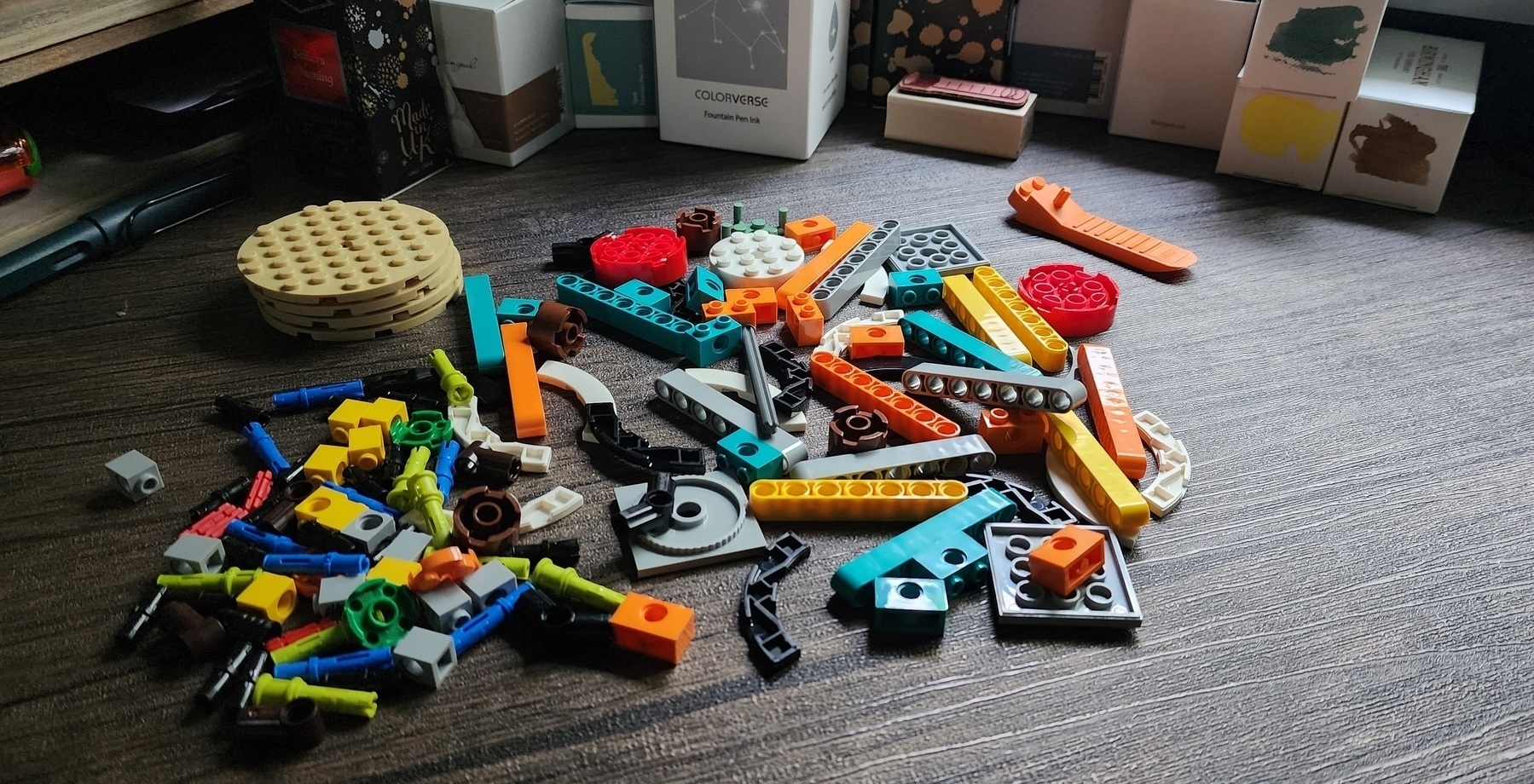 A bag of colorful Lego pieces of all shapes and sizes dumped into a pile in the middle of a desk.